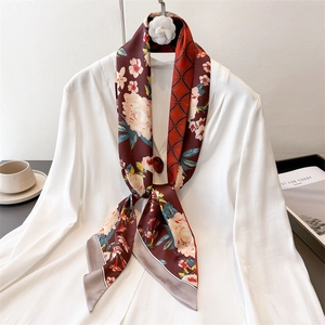 Dettaglio di sciarpa in seta bordeaux a fiori con camelia bianca su una camicia bianca