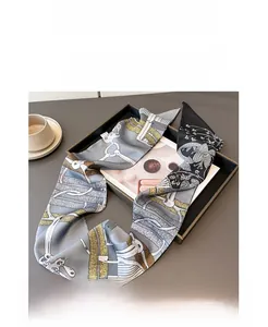 Close-up of a twilly silk scarf with equestrian chain patterns on a decorative tray