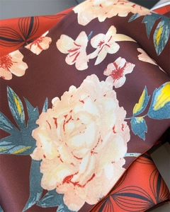 Dettaglio macro del foulard in seta con motivi floreali bordeaux e rosa raffinati