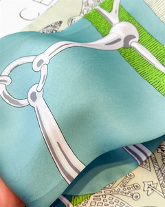 Close-up of silk scarf with green horsebit print showing smooth texture and sheen