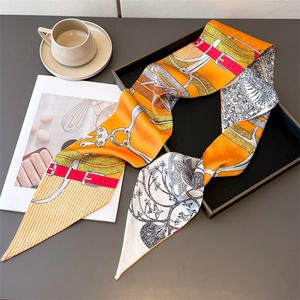 Detail of a vintage orange twilly silk scarf with chain print on a black decorative tray