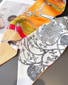 Close-up of dual silk scarves featuring orange equestrian patterns and floral bird motifs