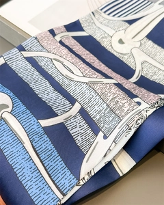 Macro detail of silk scarf showing vintage chain buckle patterns and smooth fabric texture