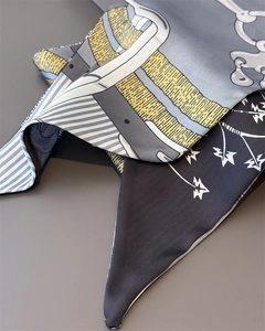Detailed view of silk twilly scarf with chain patterns and equestrian motifs