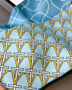 Detailed view of the smooth silk texture and vibrant geometric letter print on the scarf