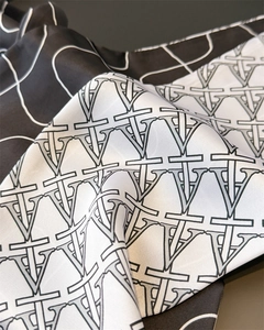 Macro shot of silk texture neckerchief featuring monochrome geometric V logo prints
