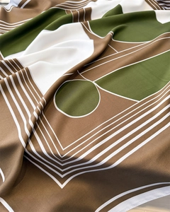 Detailed close-up of geometric silk scarf with olive green and brown patterns
