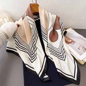 Elegant geometric print silk scarf with brown dots on white, displayed on a wooden hanger