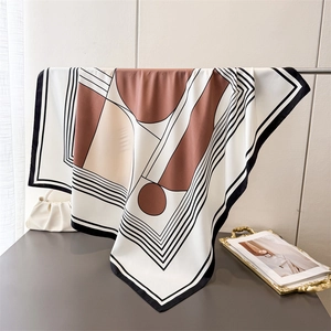 Macro shot of geometric print silk-like scarf showing smooth texture and elegant drape