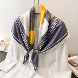 Silk-like geometric pattern scarf in yellow and grey draped on white blazer