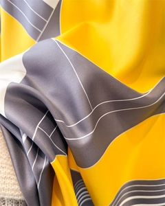 Detailed macro view of geometric silk-like scarf with twill texture and yellow patterns