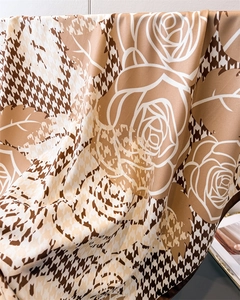 Detailed view of luxury houndstooth and rose print silk scarf with elegant brown tones