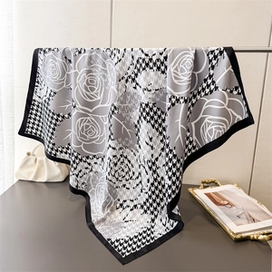 Detail of silk-like scarf featuring grey rose patterns and black houndstooth print