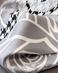 Detailed view of houndstooth silk scarf featuring abstract floral print and twill texture