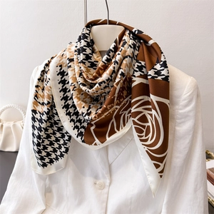 Close-up of silk houndstooth scarf with brown floral patterns on white blazer