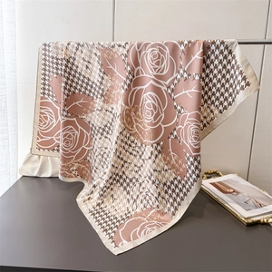 Detail of silk-like scarf featuring pink houndstooth patterns and abstract roses