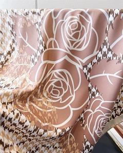 Detail of silk-like scarf featuring classic houndstooth and rose print with satin luster