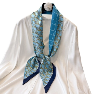 Sky blue skinny silk scarf with geometric letter patterns tied on a white shirt collar