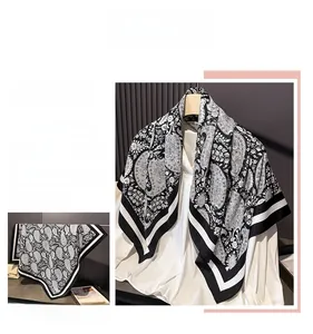 Detail of black and white paisley print scarf with sleek silk texture and striped borders