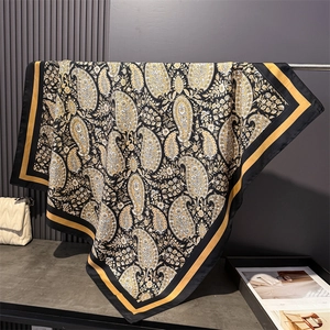 Macro detail of silk-like paisley scarf fabric with gold patterns and soft drape texture