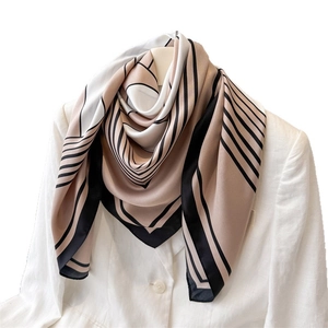 Modern geometric silk scarf featuring abstract beige and black patterns on a white blazer