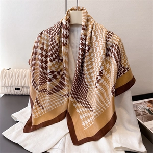 Elegant houndstooth silk-like square scarf in warm brown and khaki draped on a hanger