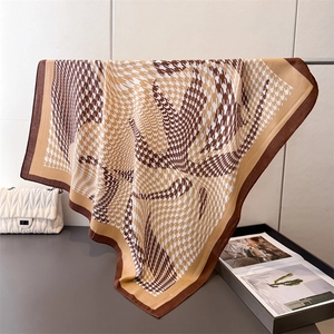Classic houndstooth silk scarf in brown and gold displayed hanging on a rack