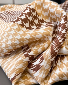 Close-up of soft houndstooth silk scarf fabric showing elegant brown and white textures