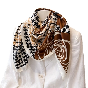 Luxurious houndstooth silk scarf with floral print draped over a stylish white blazer