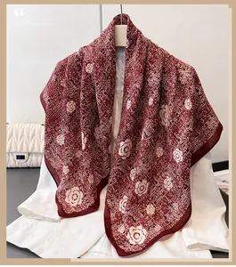 Gros plan d'un foulard en soie bordeaux avec motifs camélia blanc sur un blazer blanc