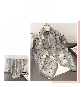 Détail du motif camélia et des coutures fines sur le foulard en soie grise