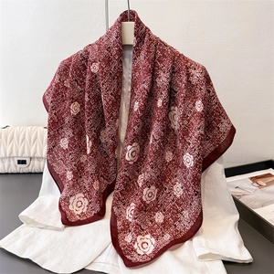 Carré en soie bordeaux à motif camélia drapé sur un blazer blanc élégant