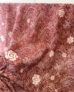 Détail de l'imprimé camélia et de la texture à chevrons sur le foulard en soie rouge