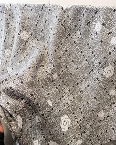 Gros plan sur un foulard en soie avec imprimé camélia, pois noirs et texture chevrons