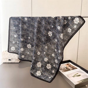 Détail d'un foulard en soie avec imprimé camélia et motif à chevrons sur un cintre
