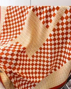 Détail d'un foulard en soie avec damier orange et motifs de calligraphie arabe élégants