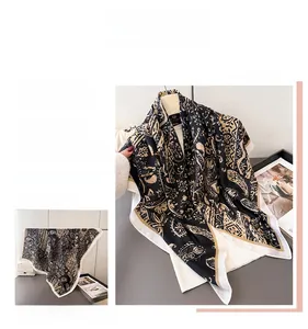 Detailed pattern of paisley silk-like square scarf with elegant gold and black floral motifs
