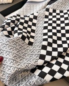 Détail de l'écharpe en soie à carreaux montrant la texture à chevrons et les motifs floraux