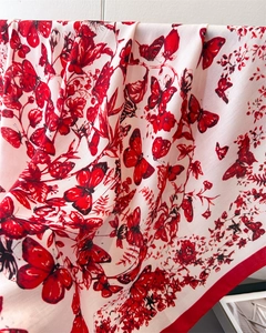 Détail d'un foulard en soie avec imprimés papillons rouges, fleurs et texture sergé