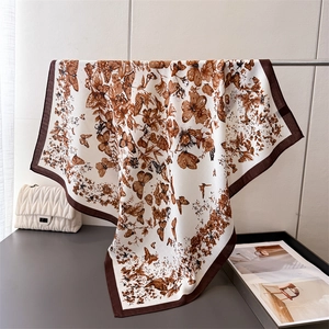 Vue détaillée d'un foulard en soie à imprimé floral et papillon avec bordure marron