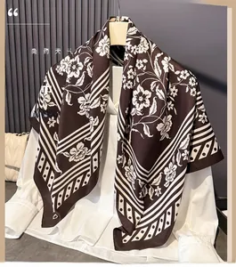 Detail of silk-like scarf with large floral print and geometric stripes on hanger