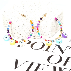 Bohemian colorful beaded hoop earrings with evil eye charms on textured stone