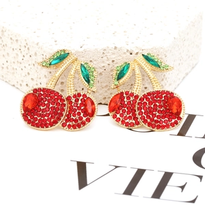 Macro shot of cherry stud earrings featuring vibrant red crystals and green leaf accents