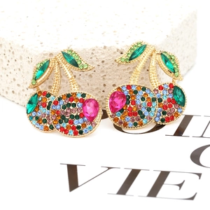 Close-up of colorful rhinestone-encrusted cherry earrings with gold finish and green leaves