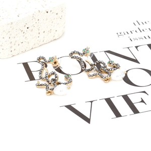 Retro gold snake earrings with grey rhinestones and baroque pearl drops on white stone