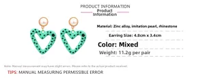 Macro view of green heart earrings with pearls and rhinestones showing size dimensions