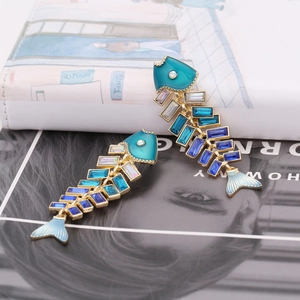 Detailed macro view of enamel fishbone earrings with colorful rhinestones on a magazine