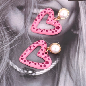 Pink heart-shaped drop earrings with crystals and pearl studs on fashion magazine