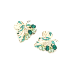 Detailed view of hollow leaf earrings with green crystals and gold-plated finish