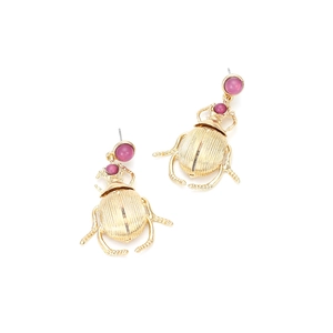 Close-up of gold beetle earrings featuring polished purple gemstone accents and textures